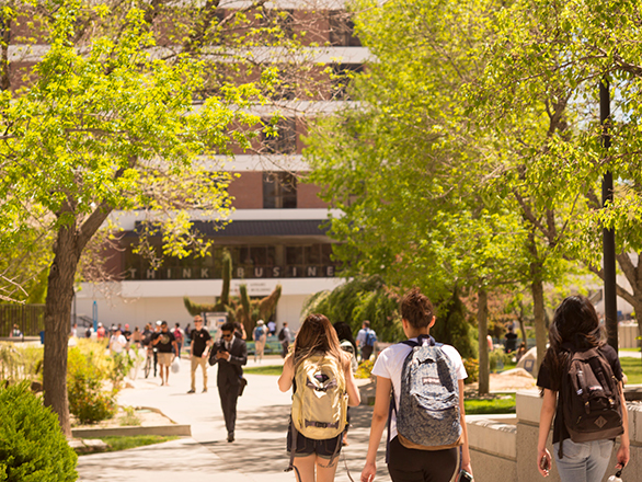 People walking near the lower quad of the University of Nevada, Reno with the business building in the background.